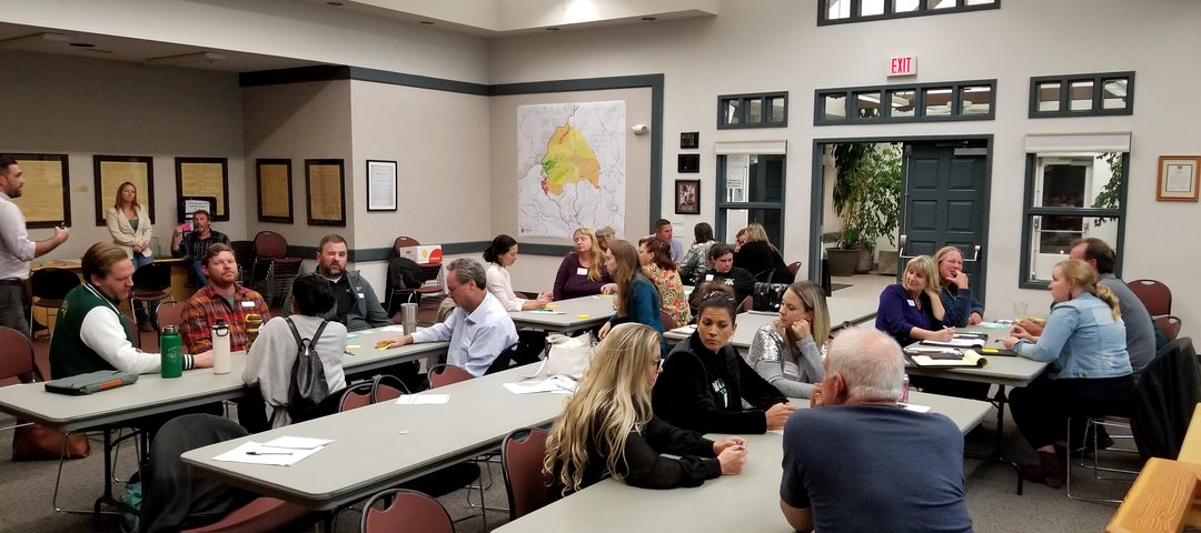 Residents seated at tables for a community meeting in a Mariposa County hall.