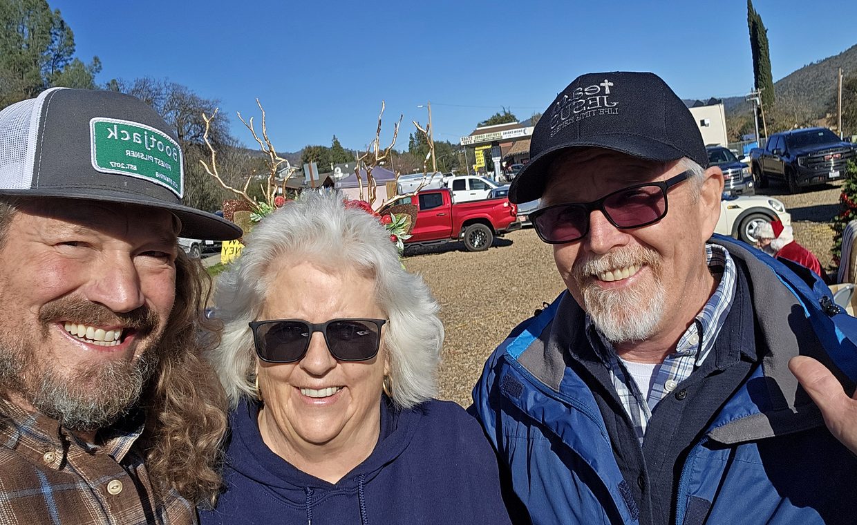 Xav and two collaborators smiling outdoors at a Mariposa community event.